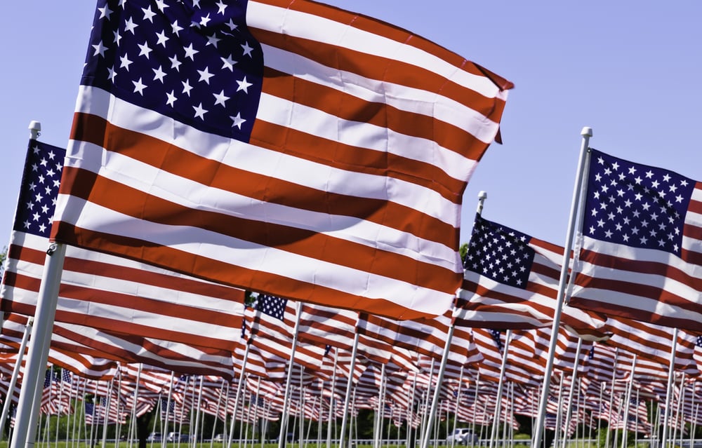 Many American flags flapping in the wind together on a national holiday